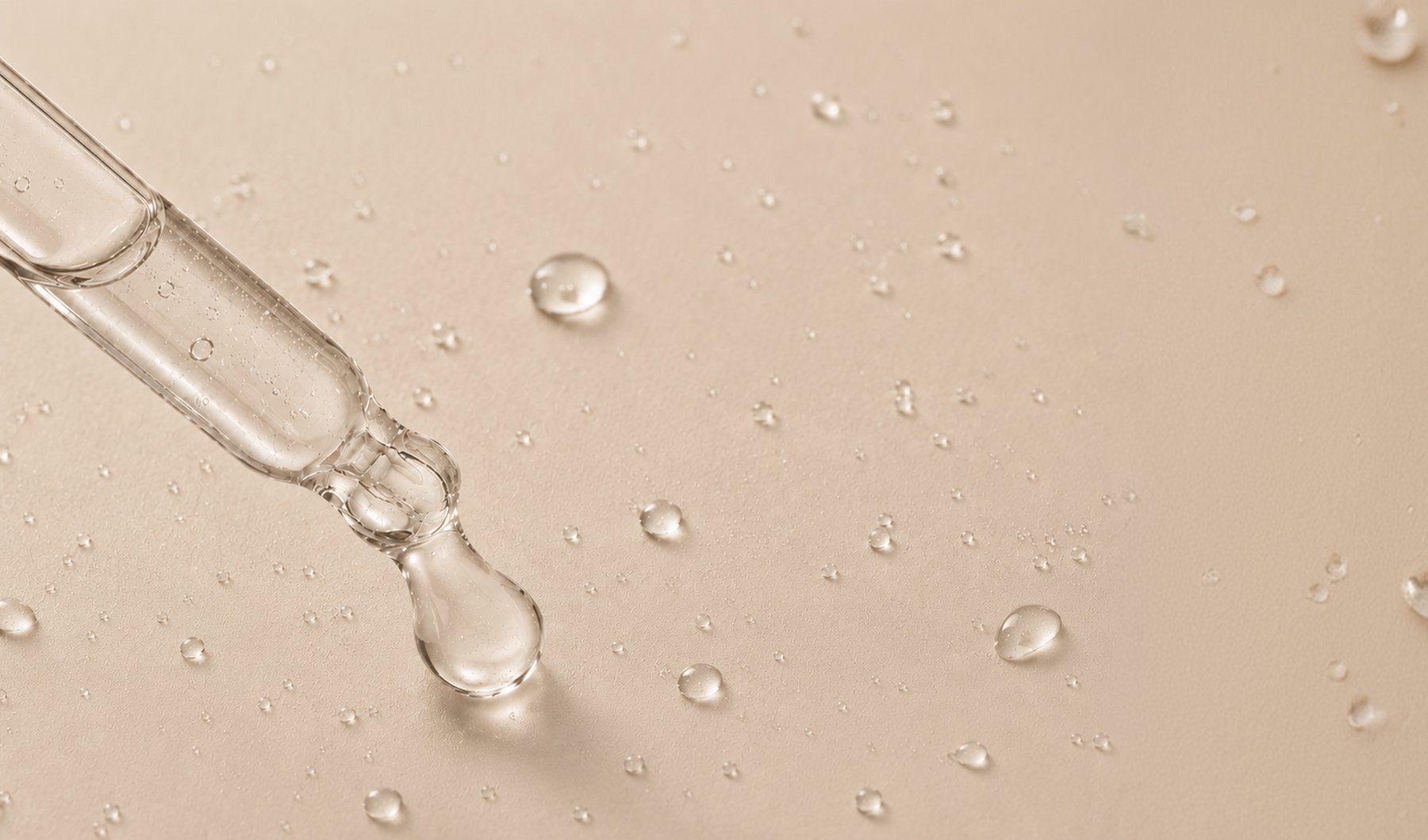 A glass pipette releasing a drop of clear serum onto a bare surface