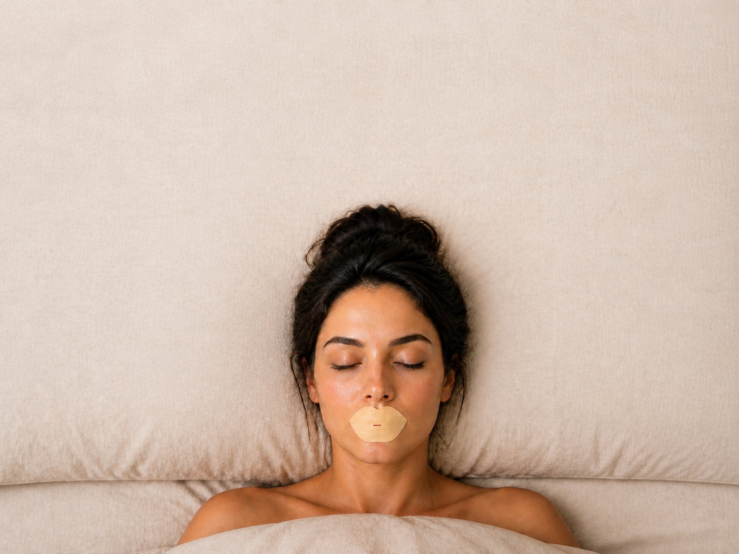 A woman asleep on her back wearing Sleep Karma hydrating bamboo mouth tape